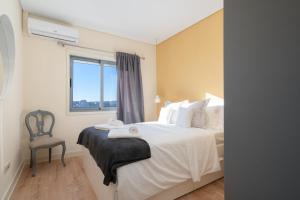 um quarto com uma cama com uma cadeira e uma janela em Gaya Avenue Flats - Elegant Contemporary Flats with Balcony em Vila Nova de Gaia