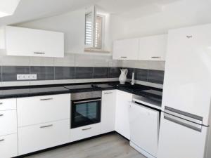 a kitchen with white cabinets and black counter tops at Apartments Bezek in Trstenik