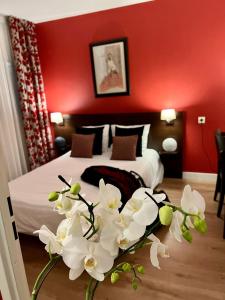 - une chambre avec un lit aux murs rouges et des fleurs blanches dans l'établissement Appartéa Grenoble Alpexpo, à Grenoble