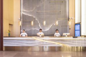 three people sitting in a lobby with their laptops at Atour Hotel Xiamen Jimei Lake Business Center in Xiamen