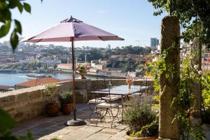 a patio with a table and chairs and an umbrella at CASA CAMÉLIA in Porto