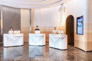 three people sitting at tables in a lobby with their laptops at Atour Hotel Jinan Quancheng Plaza Kuanhouli in Jinan