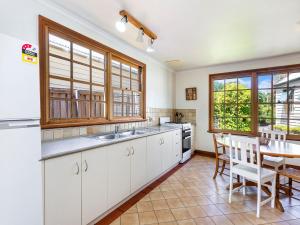 una cucina con mobili bianchi, tavolo e sedie di Lavender Cottage a Port Fairy