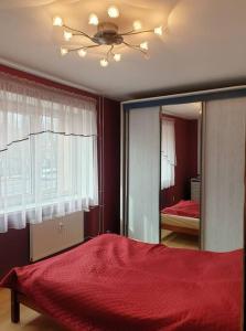 a bedroom with a red bed and a mirror at Klaipėdos miesto centras in Klaipėda