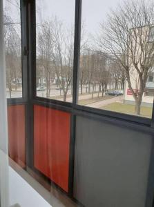 ein Fenster mit Blick auf eine Straße und Bäume in der Unterkunft Klaipėdos miesto centras in Klaipėda