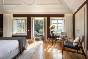 a bedroom with a bed and a chair and windows at CASA CAMÉLIA in Porto