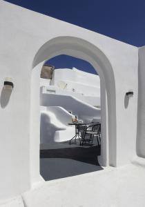 梅薩雷亞的住宿－Church and Cave - Santorini Private Residences，白色的建筑,在庭院里设有桌子