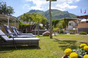 a group of chairs in a yard with mountains in the background at Hotel Parco Delle Agavi in Forio d'Ischia