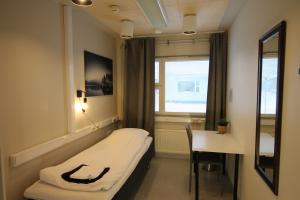 a hospital room with a bed and a desk and a window at Teemahostel in Toivakka