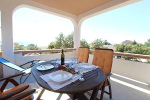 stół z butelką wina i kieliszkami na balkonie w obiekcie Apartments Karas on the island of Pag w mieście Mandre