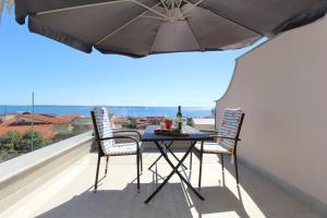a table with two chairs and an umbrella on a balcony at Apartments Karas on the island of Pag in Mandre