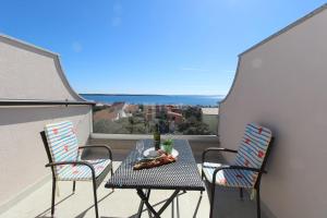 a table and chairs on a balcony with a view at Apartments Karas on the island of Pag in Mandre
