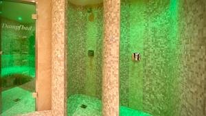 ein Badezimmer mit einer grün gefliesten Dusche und einem Spiegel in der Unterkunft Moselstern Hotel Brixiade &Triton in Cochem