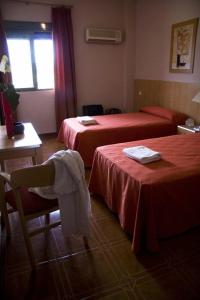 a hotel room with two beds and a table and chairs at Hotel Las Terrazas in Albolote