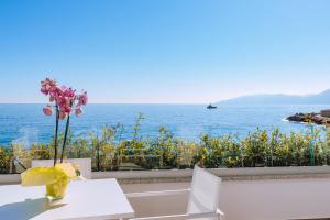 una mesa con un jarrón de flores sobre el océano en Hotel Caramare, en Cala Gonone