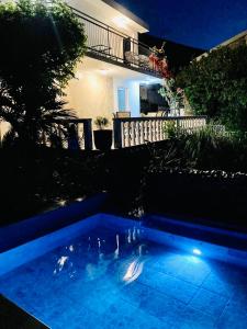 - une piscine en face d'une maison la nuit dans l'établissement Apartments Obradovic, à Krasići