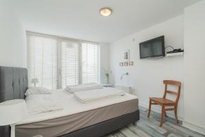 ein weißes Schlafzimmer mit einem Bett und einem Stuhl in der Unterkunft Standleven appartement 106 - Groote Keeten in Callantsoog