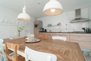 eine Küche mit einem Holztisch und weißen Stühlen in der Unterkunft Standleven appartement 106 - Groote Keeten in Callantsoog