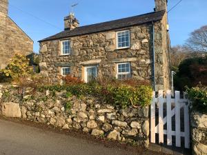 an old stone house with a white fence at Beautiful Cottage near Harlech with ocean views in Llanfair