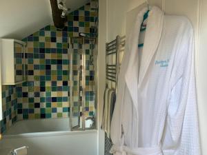 a bathroom with a robe hanging next to a bath tub at Beautiful Cottage in Llanfair with ocean views in Llanfair