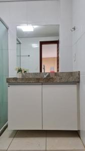 um balcão de casa de banho com um lavatório e um espelho em Flat no Club Meridional de Carneiros - Bloco 4-2PP em Tamandaré