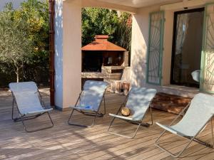 2 chaises assises sur une terrasse couverte avec une cheminée dans l'établissement Villa les écureuils, à Fréjus