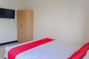 - une chambre avec un lit et une couverture rouge dans l'établissement RedDoorz At Pelangi Guest House, à Balikpapan