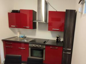 a kitchen with red cabinets and a black refrigerator at Panorama Apartmenthaus in Vöcklamarkt