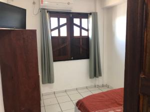a room with a window and a bed and a television at Pousada Tranquila in Morro de São Paulo