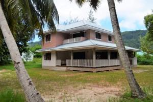 拉迪格島的住宿－L’étang Résidence，一座粉红色的房子,前面有棕榈树