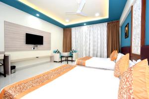 um quarto de hotel com duas camas e uma televisão de ecrã plano em The Sky Imperial- Hotel Gopal Darshan em Nathdwara