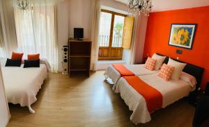two beds in a room with orange walls at Gran Hostal San Segundo in Ávila