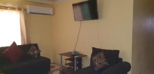 a living room with a couch and a tv on the wall at Signature comfort in Arima