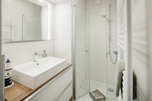 a white bathroom with a sink and a shower at Winkelschiffchen IV mit Sauna in Juist +73 photos