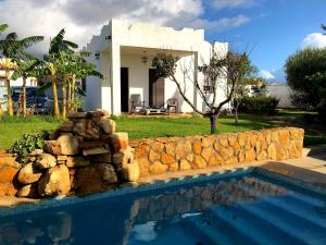 una casa con una pared de piedra y una piscina en Alojamientos Rurales Inma, en Conil de la Frontera