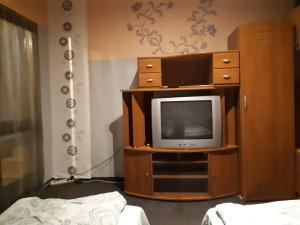 a room with a tv on a wooden entertainment center at Sárkány Lak Budapestnél in Budapest