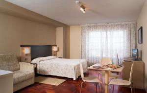 a bedroom with a bed, desk, chair and a lamp at Apartamentos Attica21 Portazgo in A Coruña