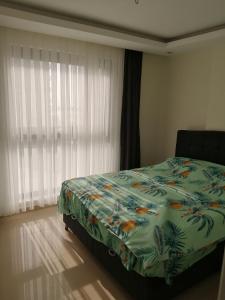 a bedroom with a bed with a green comforter and a window at Siberland olive garden 1+1 residence spa - pool in Alanya