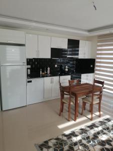 a kitchen with white cabinets and a wooden table and chairs at Siberland olive garden 1+1 residence spa - pool in Alanya