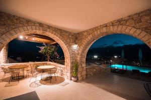 an outdoor patio with tables and chairs and a stone wall at Melies Hotel in Kokkinórrakhi