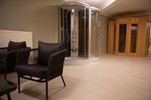 a bathroom with a shower and a chair and a tub at V8-Kelemen Panzió in Makó