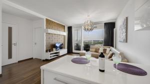 eine Küche und ein Wohnzimmer mit einem Tisch und Weingläsern in der Unterkunft Panorama - Sunset and castle view, 22nd floor, garage, AC in Bratislava