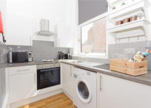 a kitchen with white cabinets and a washer and dryer at The Blakeney in Leicester