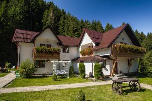 een wit huis met rode daken en een picknicktafel bij Complex Turistic Luminita in Moieciu de Sus