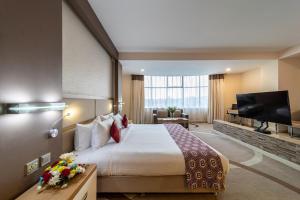 ein Hotelzimmer mit einem Bett und einem Flachbild-TV in der Unterkunft PrideInn Azure Hotel Nairobi Westlands in Nairobi