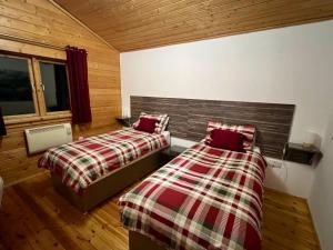 two beds in a room with wooden walls and wood floors at Tufty Lodge, Lake Pochard lodge 9 in South Cerney