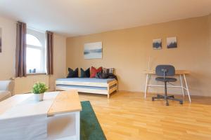 1 dormitorio con cama, escritorio y silla en FULL HOUSE Studios - Brühl's Skyline Apartment - Nespresso inkl, en Chemnitz