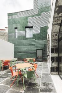 un groupe de tables et de chaises devant un bâtiment dans l'établissement Casa da Galeria - Azores Art of Hosting, à Ponta Delgada