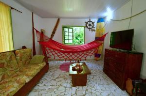 a living room with a couch and a tv at Casa à beira do rio Jaguareguava na Mata Atlântica em Bertioga SP in Bertioga