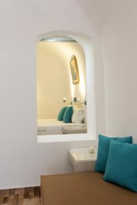 Church and Cave - Santorini Private Residences في ميساريا: مرآة على الحائط مع أريكة في الغرفة